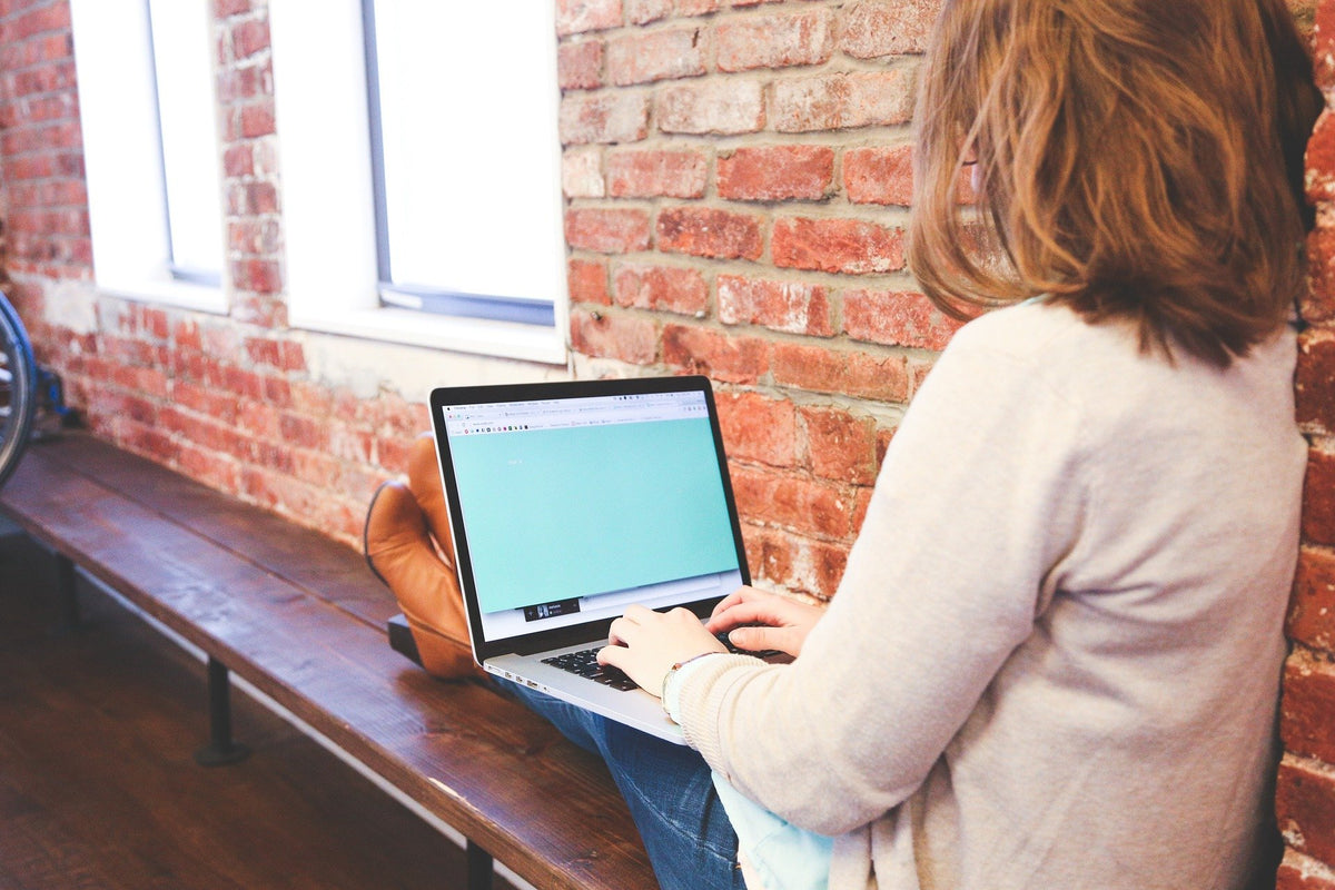 woman using a laptop on a bench
