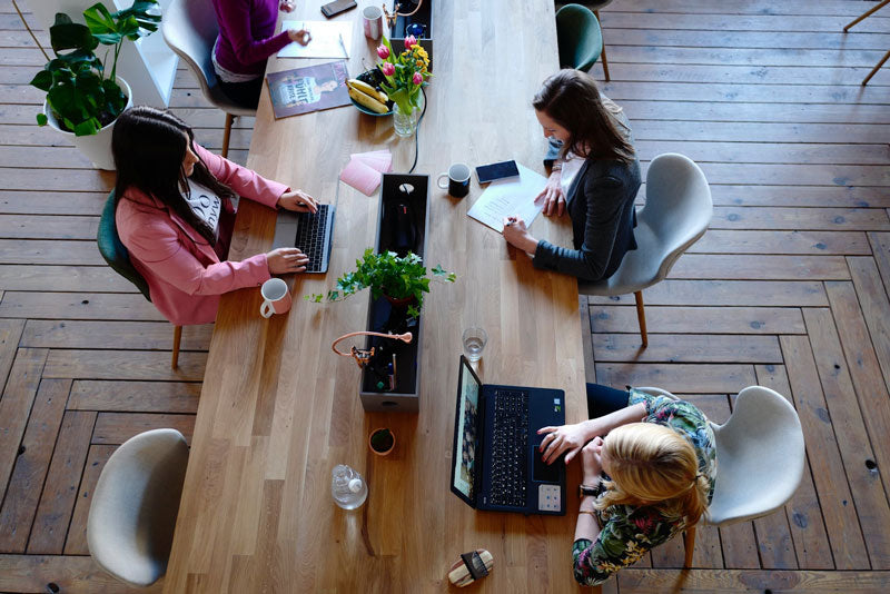 Three Women with Laptops at Shared Work Table