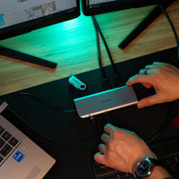 Person using a USB hub with multiple devices on a desk