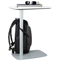 Small table with a backpack securely strapped to table and sunglasses on a white background