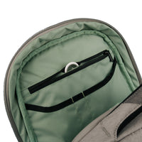 Close-up of the interior of a gray backpack showing a sage green padded compartment with a black zipper pocket and elastic band.