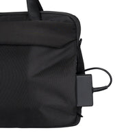 Black backpack with a power adapter attached on a white background