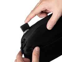 Hand zipping a black bag on a white background