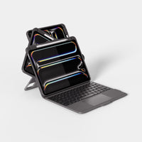 A dark gray tablet case with an attached keyboard cover, shown open and angled on a clean light gray studio background. The tablet screen displays a colorful reflective wallpaper, and the case has a protective rugged frame.