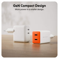 Two compact GaN chargers on a wooden surface against a soft light gray background. One charger is plain white, and the other is white with a bright orange front panel.